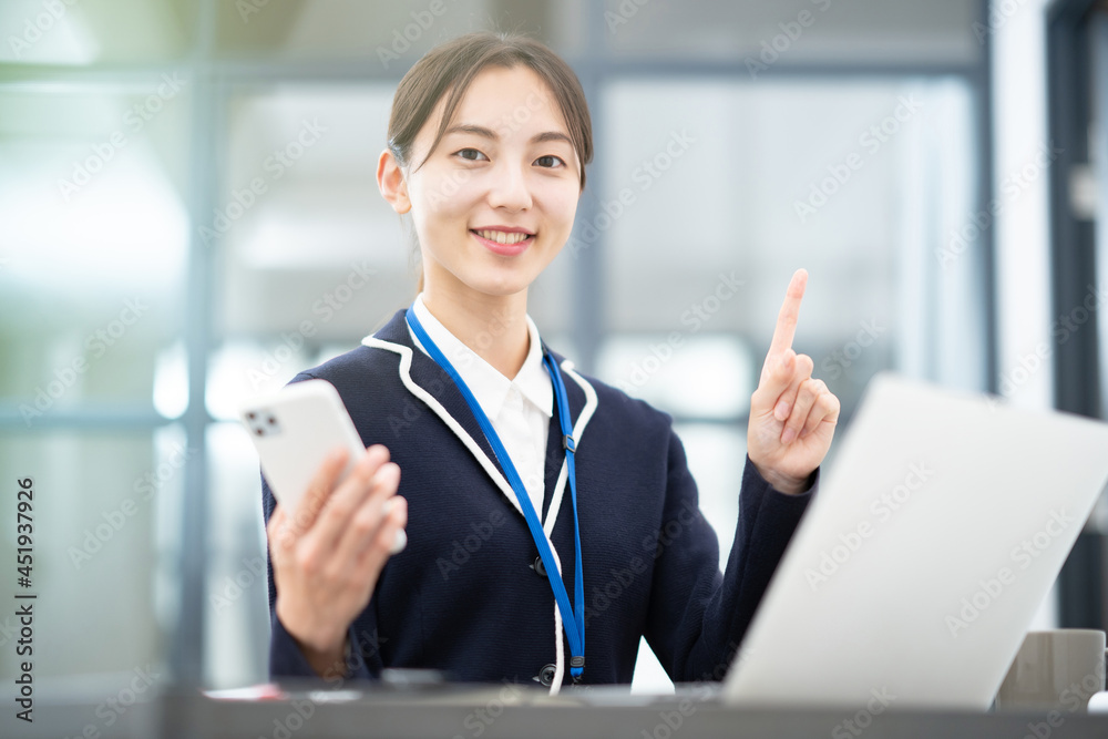 オフィスで人差し指を立てるポーズをする女性
