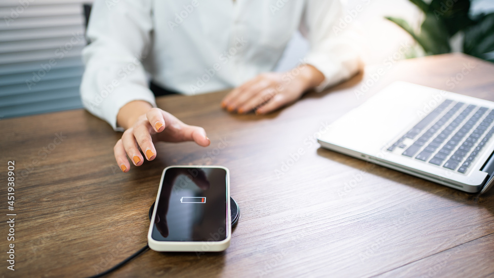 Fototapeta premium Charging mobile phone battery with wireless charging device in the table. Smartphone charging on a charging pad. Mobile phone near wireless charger Modern lifestyle technology concept.