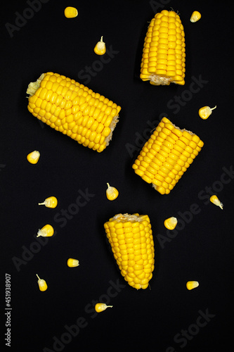 Fresh yellow sweet corn on the cob on black stone board background. For food concept. Top view