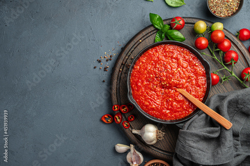 Tomato sauce with pepper, garlic and basil on a dark blue-gray background. Pasta dressing, pizza sauce.