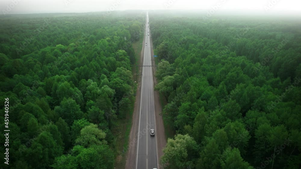 A lonely road with traffic between green forests. Smoke and smog of forest fires. An ecological concept. Saving the forests. Aerial view.