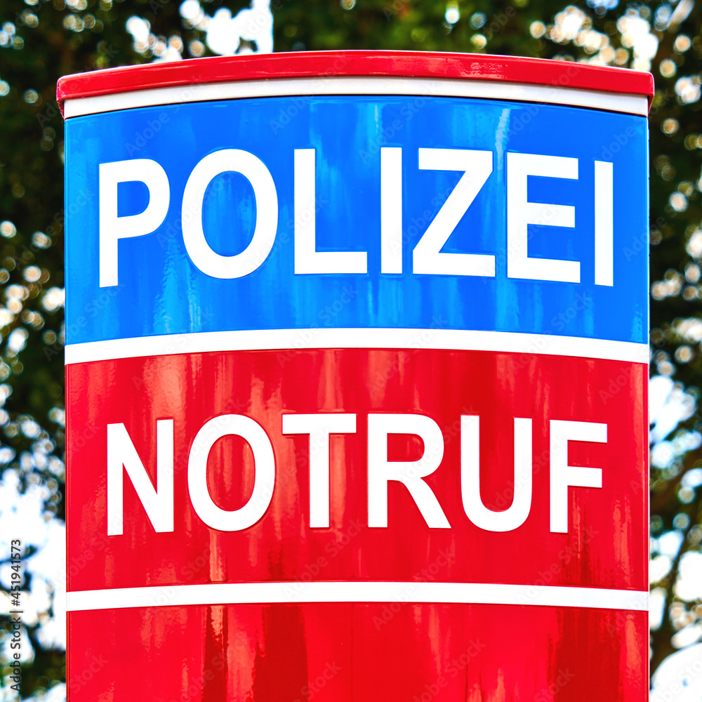 Fototapeta premium Upper part of red and blue colored emergency call pillar with German inscription Notruf und Polizei (emergency call and police)
