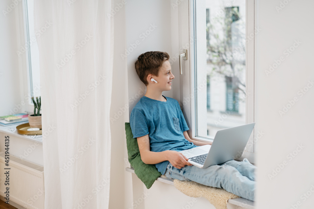 Young boy sitting on a window seat at home Young boy sitting on a window seat at home