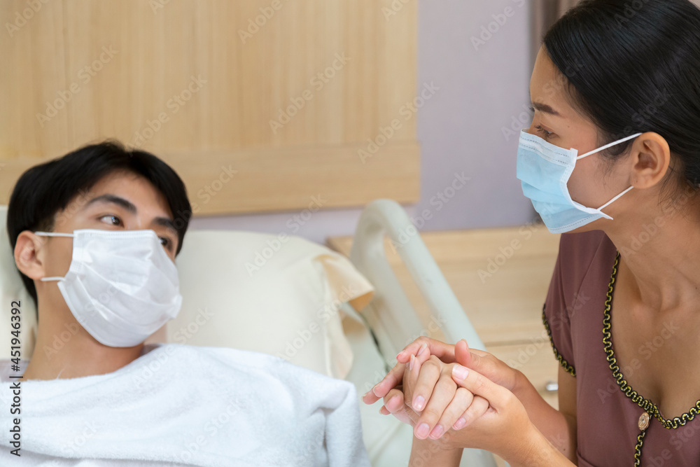 worrying asian mother holding hand and take care patient teenager son wearing protective face mask after recovery from covid quarantine treatment in hospital. family love and medical treatment.