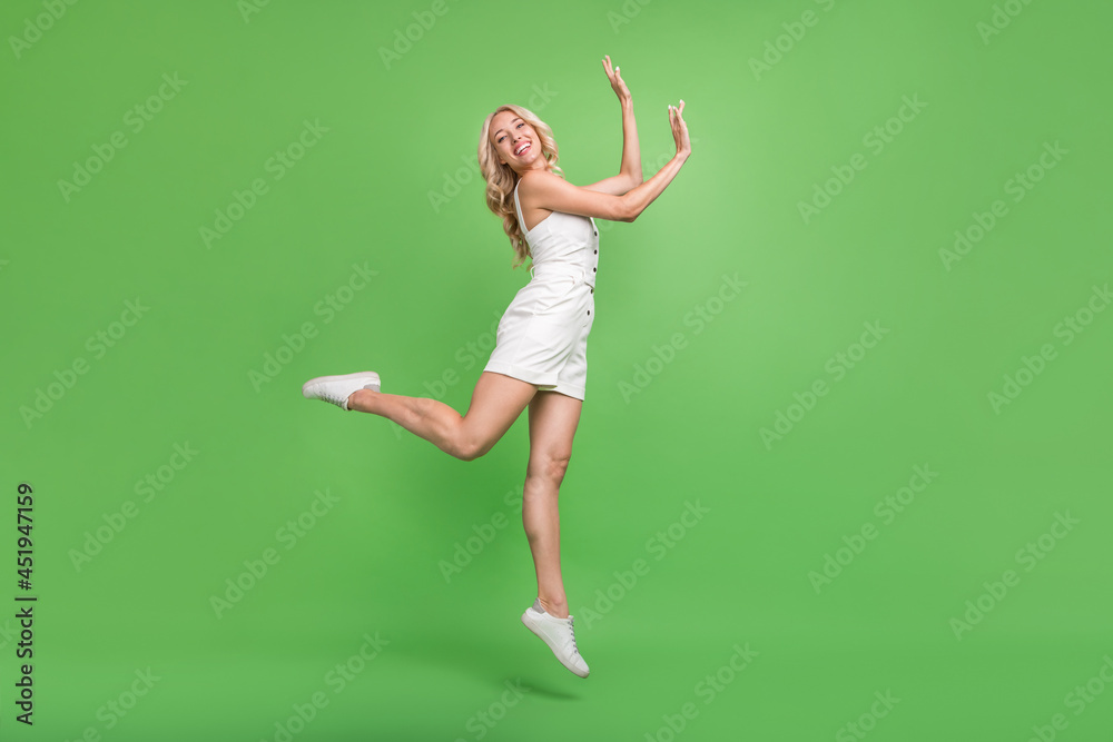 Full size profile side photo of smiling cute girl jumping dancing enjoying free time summer isolated on green color background Full size profile side photo of smiling cute girl jumping dancing enjoying free time summer isolated on green color background