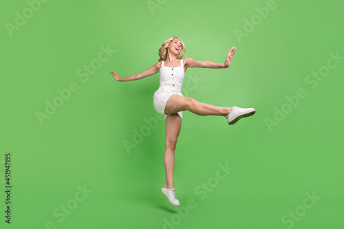 Full size photo of funky funny energetic sportive girl dancing stretching legs isolated on green color background