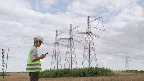 An electrical engineer forcing a drone To inspect high voltage poles before starting a project.