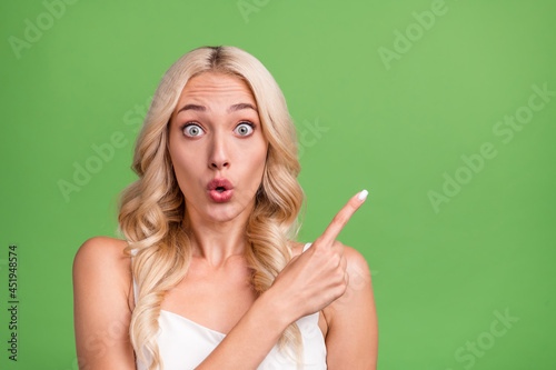 Photo of young amazed crazy girl stare haze point finger copyspace advertise product isolated on green color background