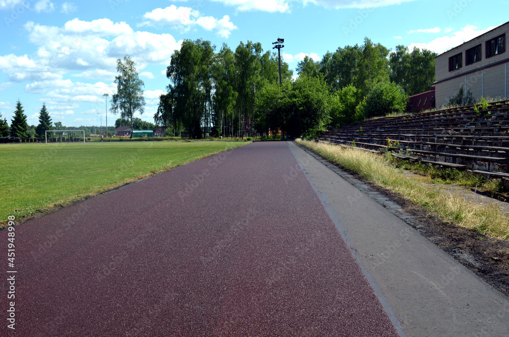 a brown-paved road that runs along ruined benches and into the forest in the background