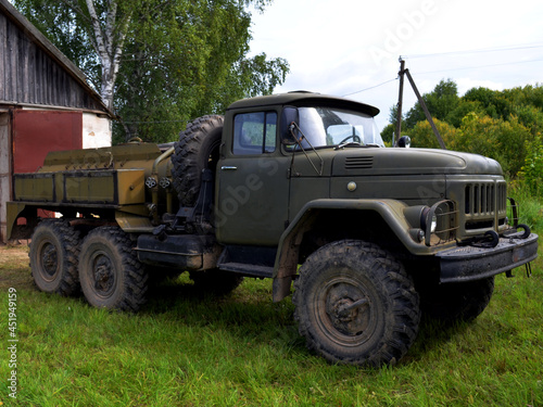an old military car with a sump drives out of the garage against the backdrop of green spaces