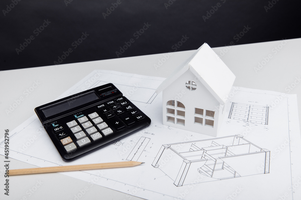Model of house and calculator on architectural project. House building budget Model of house and calculator on architectural project. House building budget