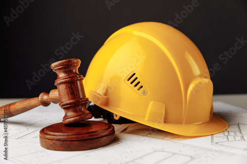 Wooden gavel with yellow helmet close-up. Construction law theme photo