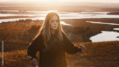 Young woman in black clothes training with a sword while sunset on nature photo