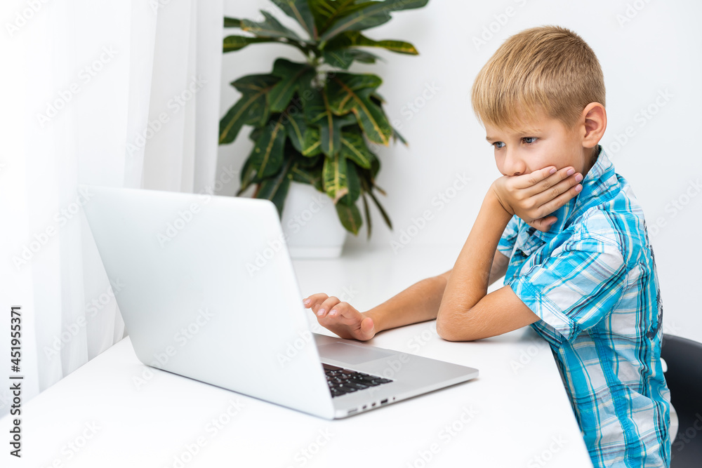 Distance learning online education. A schoolboy boy studies at home and does school homework. A home distance learning Distance learning online education. A schoolboy boy studies at home and does school homework. A home distance learning