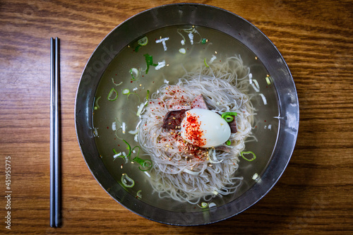 Top view of plate of pyongyang naengmyeon noodles and chopsticks on teh wooden table photo