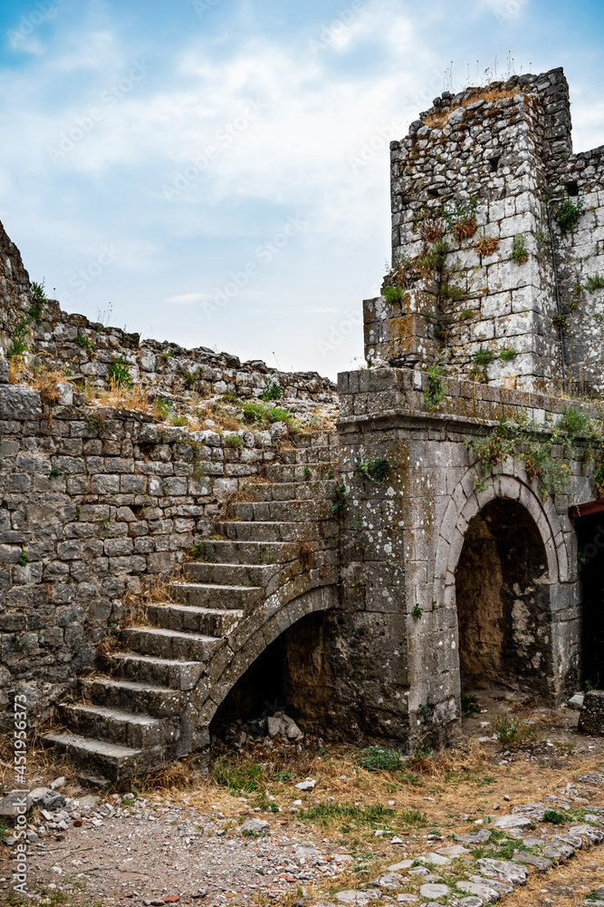 Fragment of a stone wall with arched holes and a staircase in Shkoder Castle (Albania). Ruins of a medieval European defensive fortress, vertical