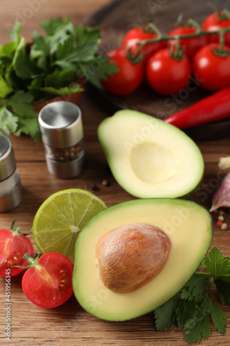 Fresh ingredients for guacamole on wooden table