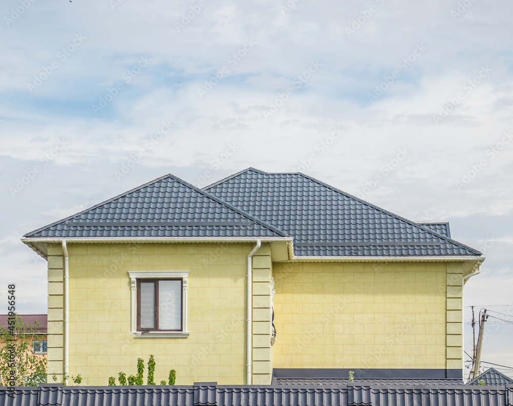 House with a new metal roof against a blue sky closeup. Roof from corrugated board