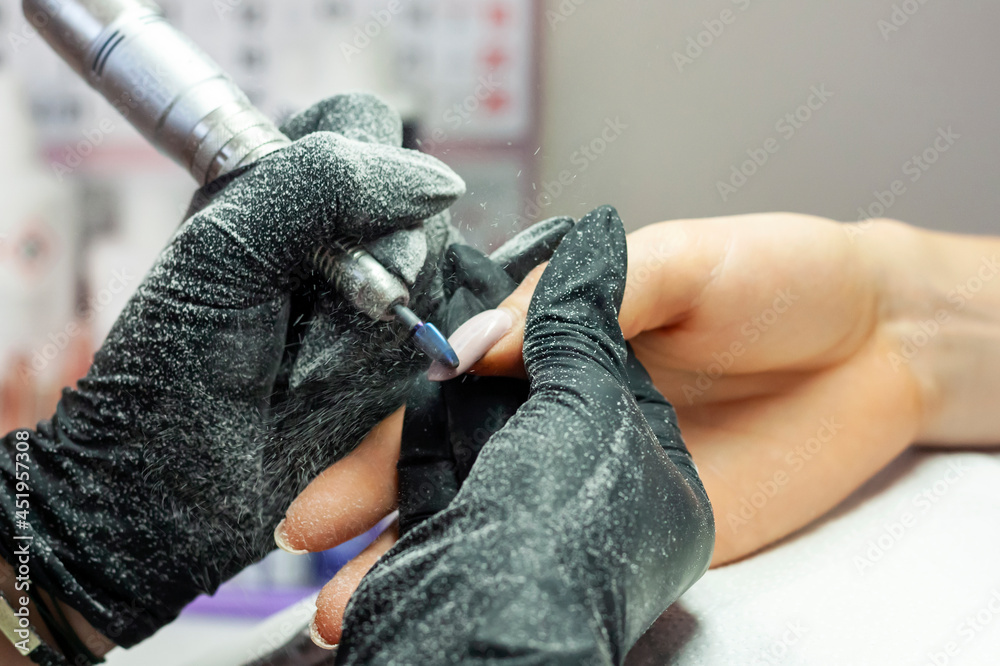 Nail stylist using a nail mill to remove the uv gel from the nails