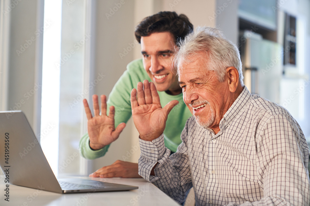Senior und junger Mann winken beim Video Streaming Senior und junger Mann winken beim Video Streaming
