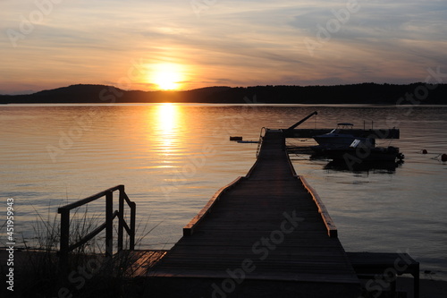 Sunset with wooden pier or deck on a calm day with sun reflecting in the sea in Norway