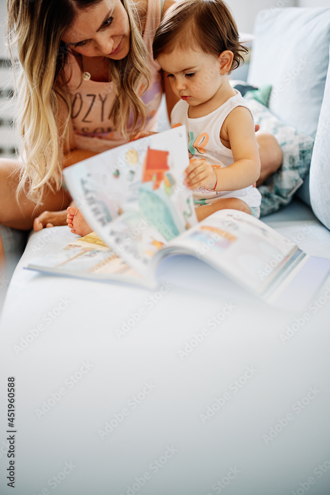 A young mother teaching her little girl how to read. A young mother teaching her little girl how to read.