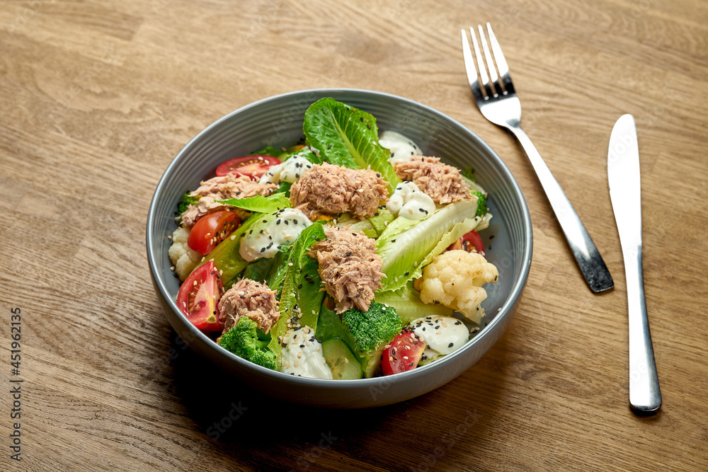 Diet salad with tuna, broccoli and cherry tomatoes in a bowl on a wooden background Diet salad with tuna, broccoli and cherry tomatoes in a bowl on a wooden background