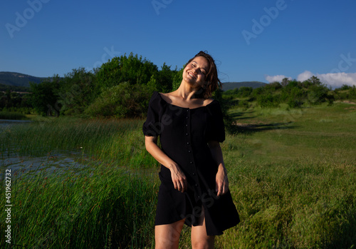 portrait of a young asian woman on the background of meadow and lake
