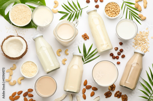 Different vegan milks and ingredients on white background  flat lay