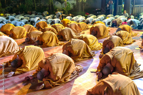 Monks and Buddhists are reverently bowing to Buddha during evening ceremony for Amitabha Buddha at an ancient temple in Ho Chi Minh City, Vietnam