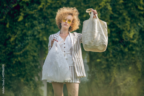 Ginger girl holding eco bag and a plastixc bag in nhands photo