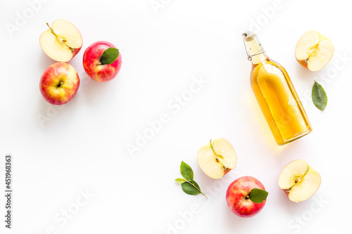 Apple cider vinegar in glass bottle with fresh red apples