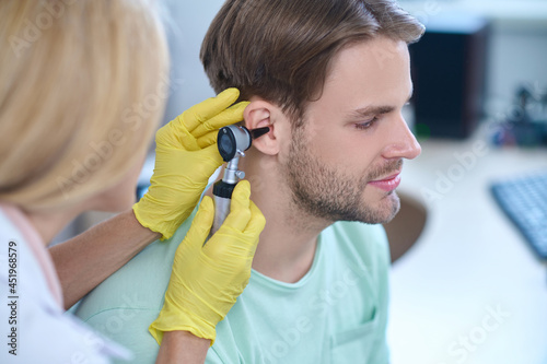 Tranquil cute man undergoing an otoscopy procedure at a clinic photo