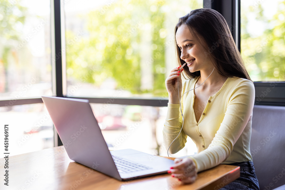 Smiling happy businesswoman in headphones sits at desk, looks at laptop screen, making notes, participating in self-improvement webinar, having fun on internet, communicating online by video call Smiling happy businesswoman in headphones sits at desk, looks at laptop screen, making notes, participating in self-improvement webinar, having fun on internet, communicating online by video call