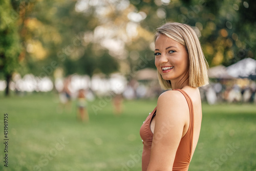 Beautiful summer portrait of a smiling woman in a swimsuit, looking at camera.