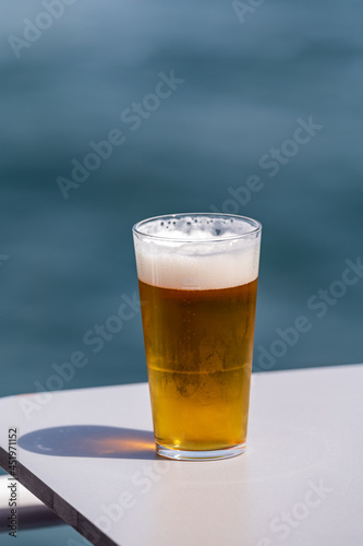 Glass of draught beer served outdoor on terrace with sea view