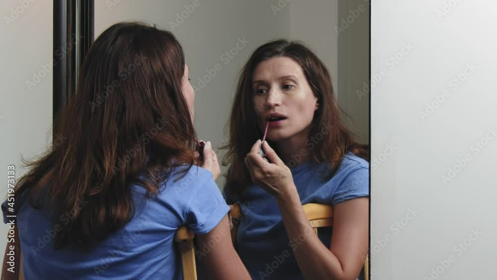 Woman standing on crutches in front of a mirror applies makeup to her face. Paints lips with lipstick. Woman standing on crutches in front of a mirror applies makeup to her face. Paints lips with lipstick.