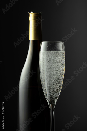 Bottle and glass of champagne on a black background.