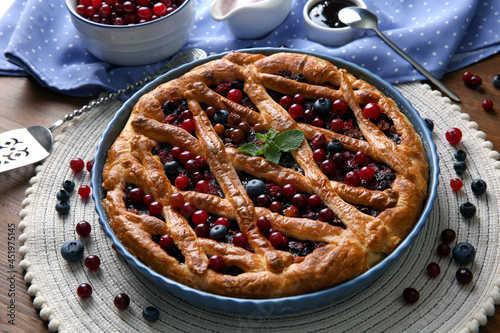 Delicious currant pie with fresh berries on wooden table