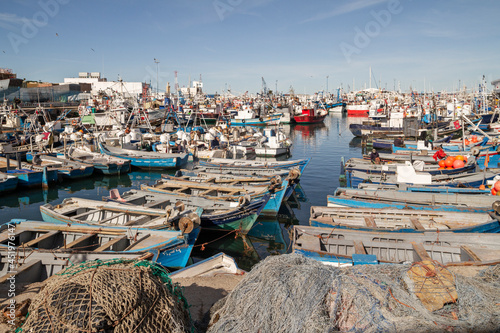 Crowd of wooden boats in a fishing port in northern Morocco with piled up fishing nets in the foreground