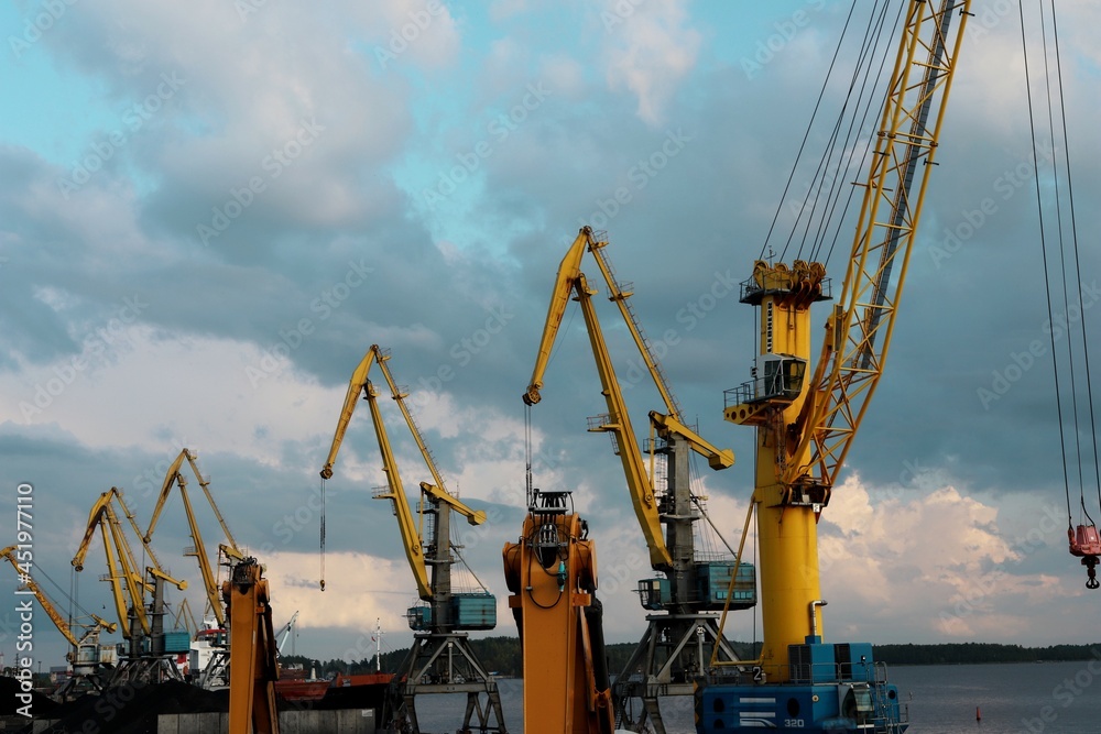 yellow cranes in the cargo river port. coal for loading into the freight train. Port in Vyborg on the Gulf of Finland yellow cranes in the cargo river port. coal for loading into the freight train. Port in Vyborg on the Gulf of Finland
