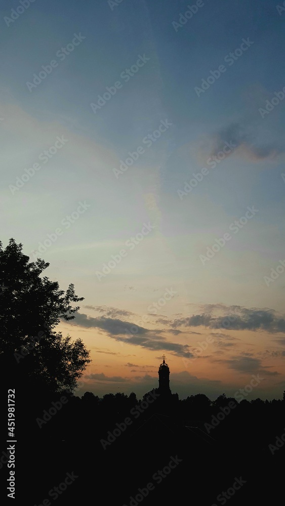 Sunset bright orange gold sky with white clouds under the church. Nature background