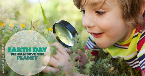 Composition of earth day logo and text over boy using magnifying glass