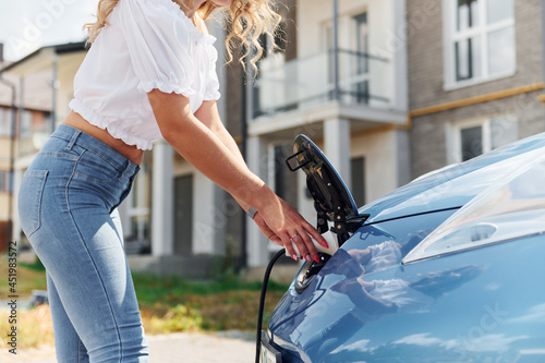 Close up view. Young woman in casual clothes with her electromobile outdoors at daytime photo