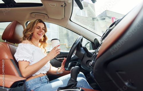 Conception of success. Young woman in casual clothes is sitting in her car at daytime