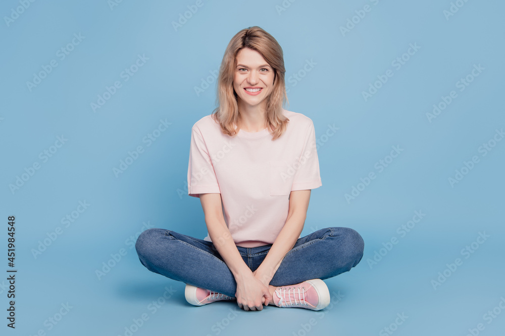 Portrait of cheerful nice girlish lady sit floor relax enjoy weekend on blue background Portrait of cheerful nice girlish lady sit floor relax enjoy weekend on blue background