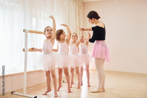 Coach teaches children. Little ballerinas preparing for performance by practicing dance moves