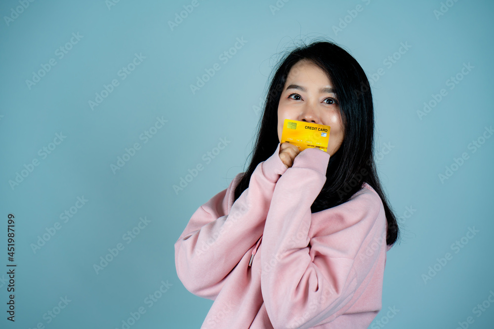 Portrait of an Asian girl wearing a pink shirt. in mobile credit card pose for a photo with a happy face Looking at the camera, behind a gray background in the studio. Portrait of an Asian girl wearing a pink shirt. in mobile credit card pose for a photo with a happy face Looking at the camera, behind a gray background in the studio.