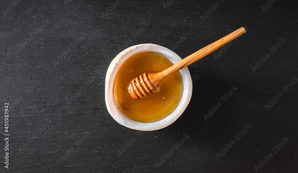 Organic and fresh honey in glass bowl isolated on black background. Healthy food concept. Organic and fresh honey in glass bowl isolated on black background. Healthy food concept.