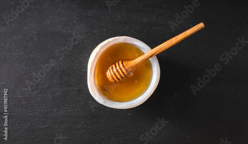 Organic and fresh honey in glass bowl isolated on black background. Healthy food concept.